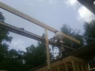 Carpenter setting a ridge beam over a new addition frame — Ice Dam Removal by Roofing Brothers in Wadesboro