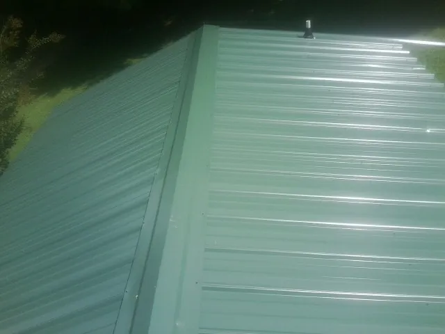 New green metal panels meeting at the ridge of a roof — Flat Roof Repair work by our crew in Wadesboro