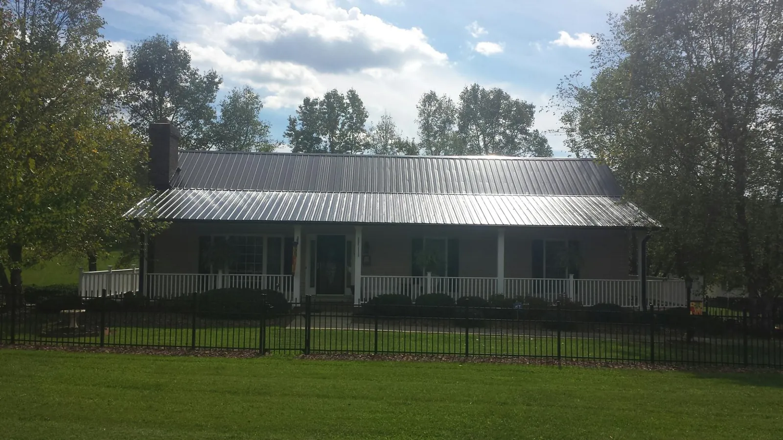 Gray metal roof on a brick ranch with a full width front porch — Gutter Guard Installation work by our crew in Wadesboro
