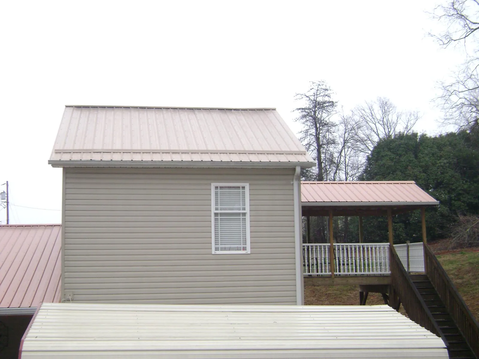 Tan metal roofs on a two story addition and attached porch, from a Roof Replacement job in Wadesboro
